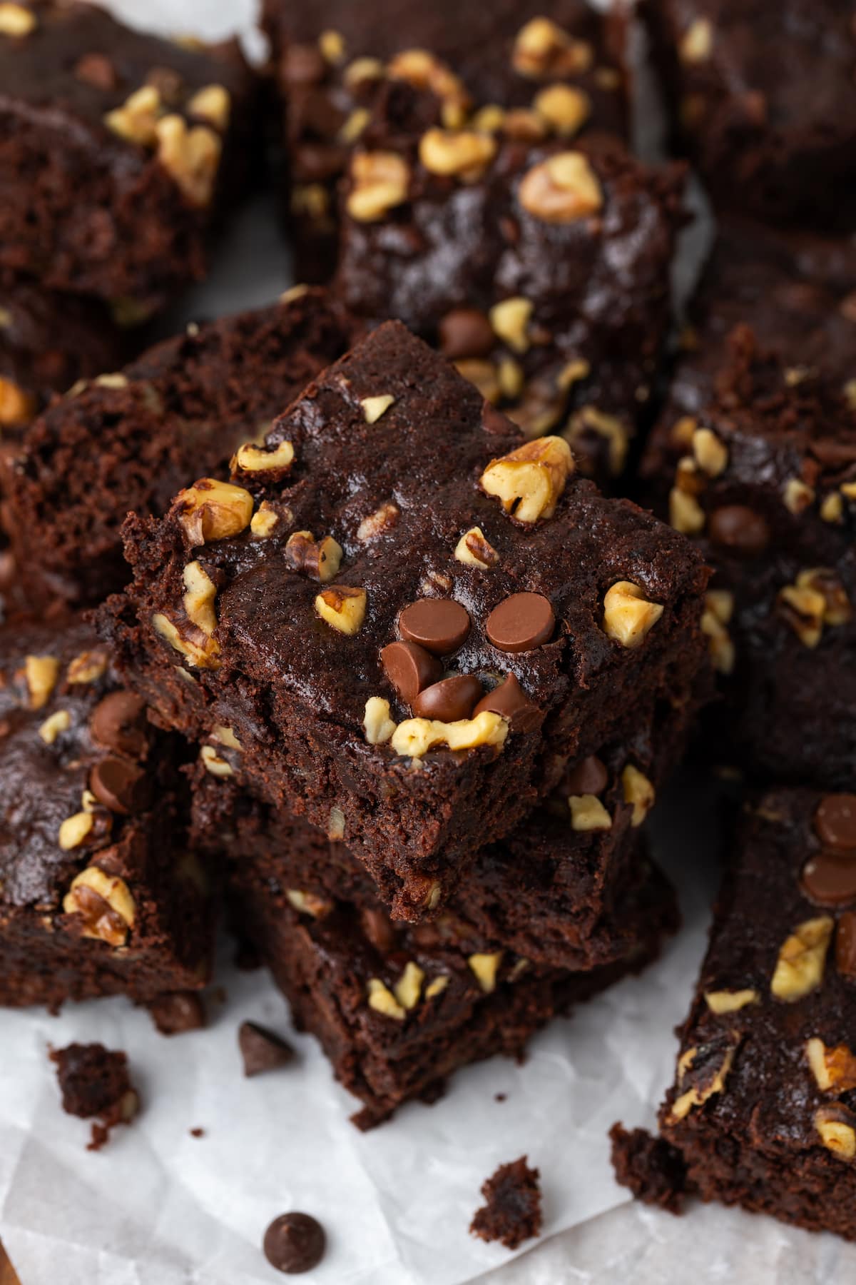 Assorted banana bread brownies stacked on top of a wooden platter lined with parchment paper.