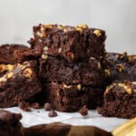 Side view of banana bread brownies stacked on top of a wooden platter lined with parchment paper.