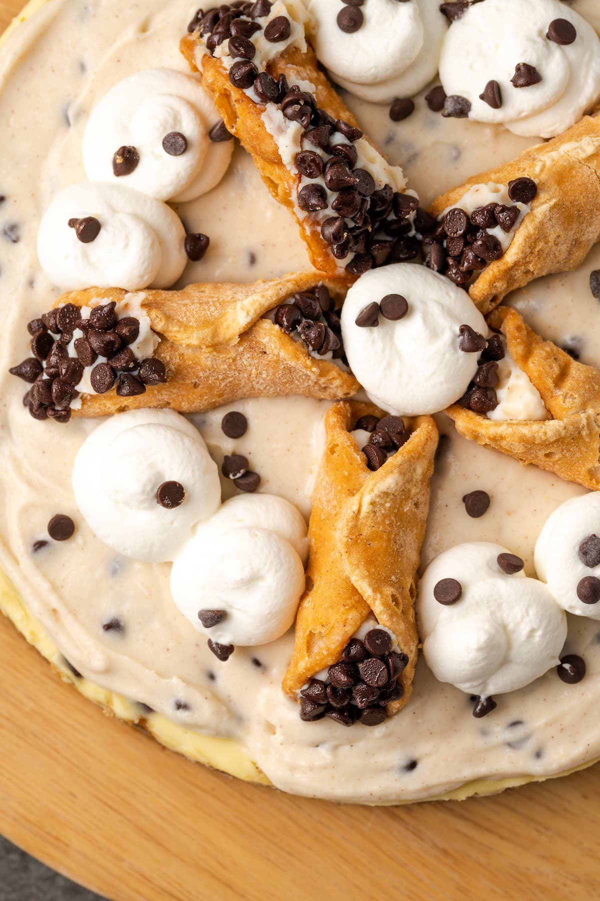 Overhead view of cannoli cheesecake decorated with swirls of whipped cream and mini cannoli pastries.