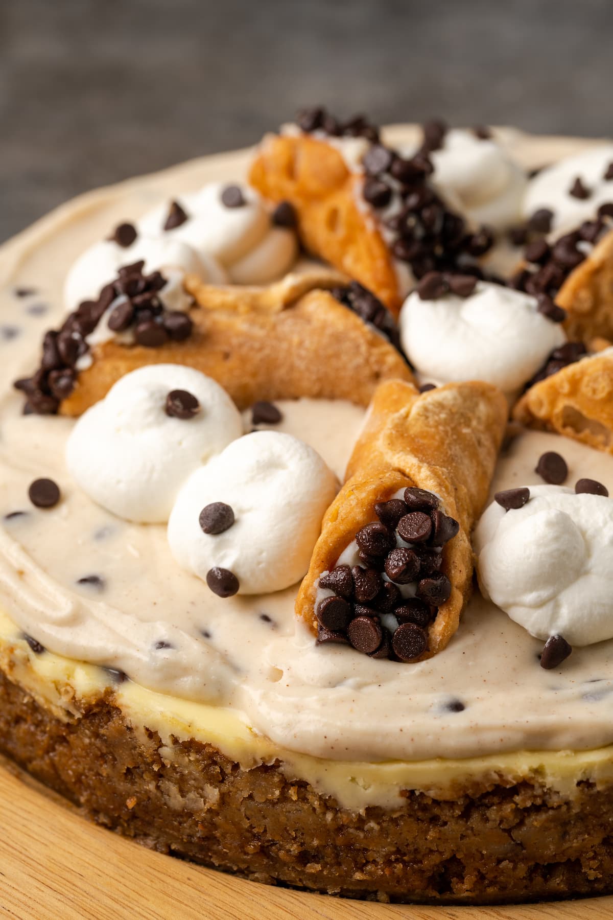 Cannoli cheesecake decorated with swirls of whipped cream and mini cannoli pastries.