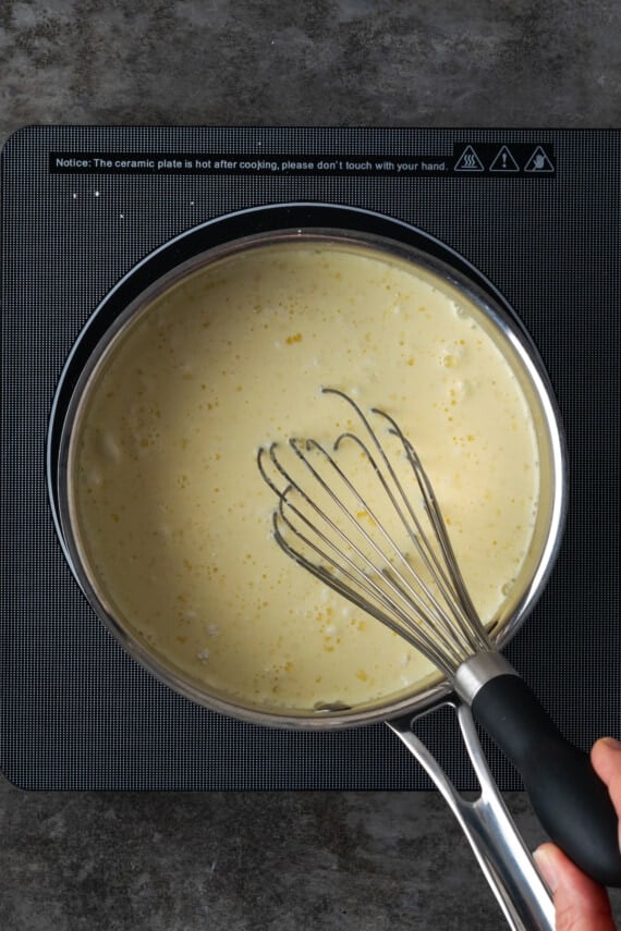 Custard in a saucepan with a whisk.