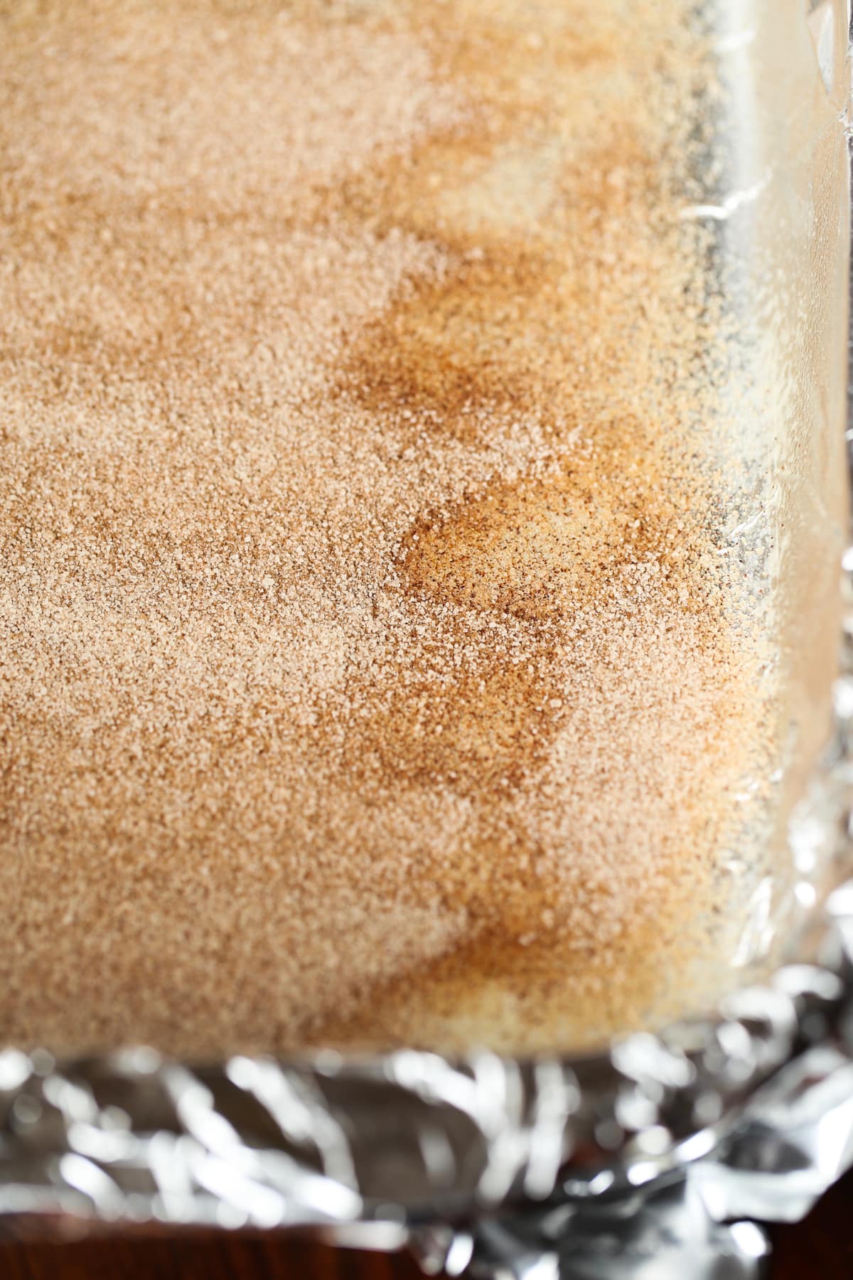 A 9x13 baking dish with cinnamon sugar coating the bottom before adding cokie dough on top.