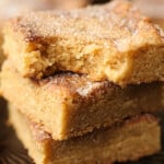 A stack of cinnamon sugar Churro cookie bars stacked with a bite taken from the top one.