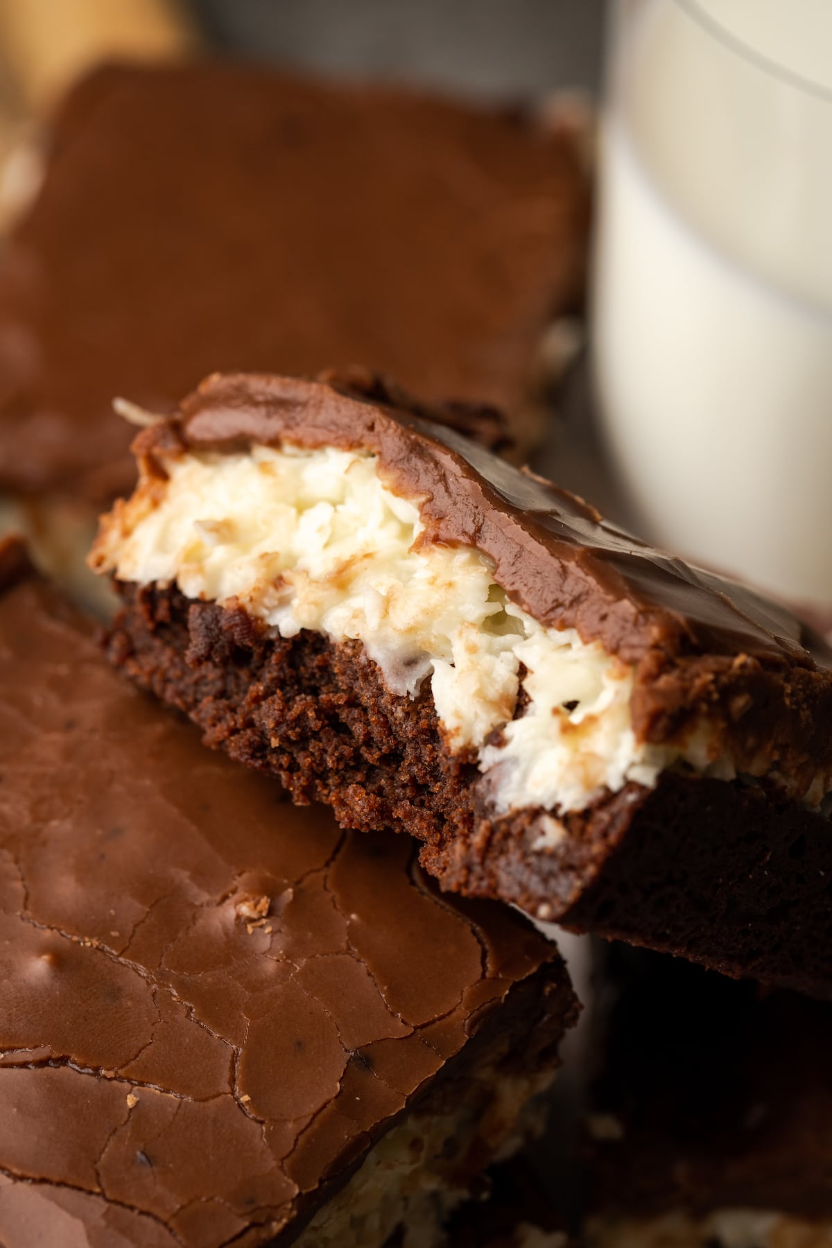 Close up of a coconut brownie leaning against another brownie, showing the coconut layer.