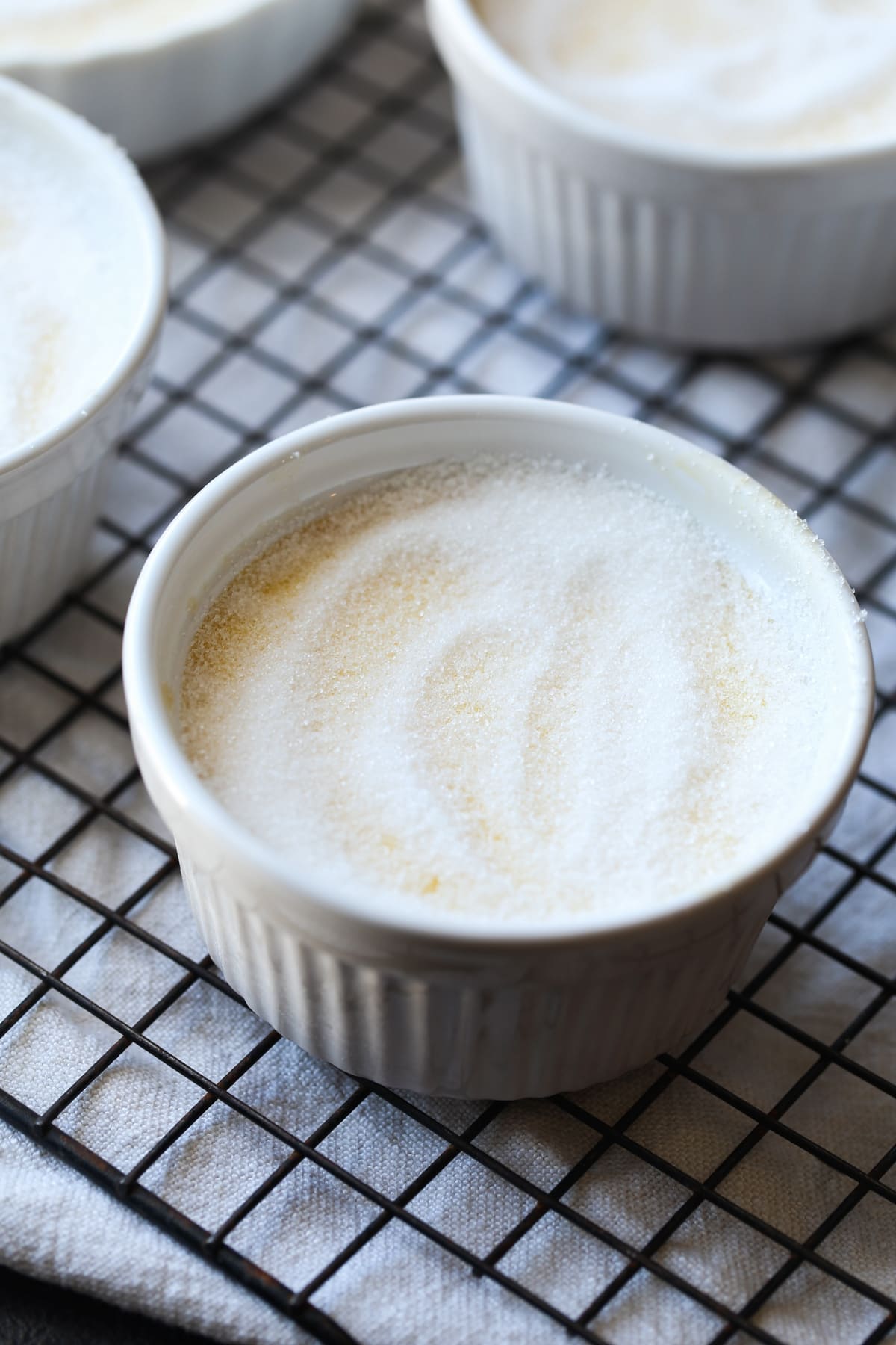 Granulated sugar on top of custard in a ramekin before using a food torch to melt the sugar