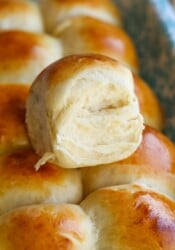 Freshly baked Hawaiian roll on top of a tray of more Hawaiian rolls