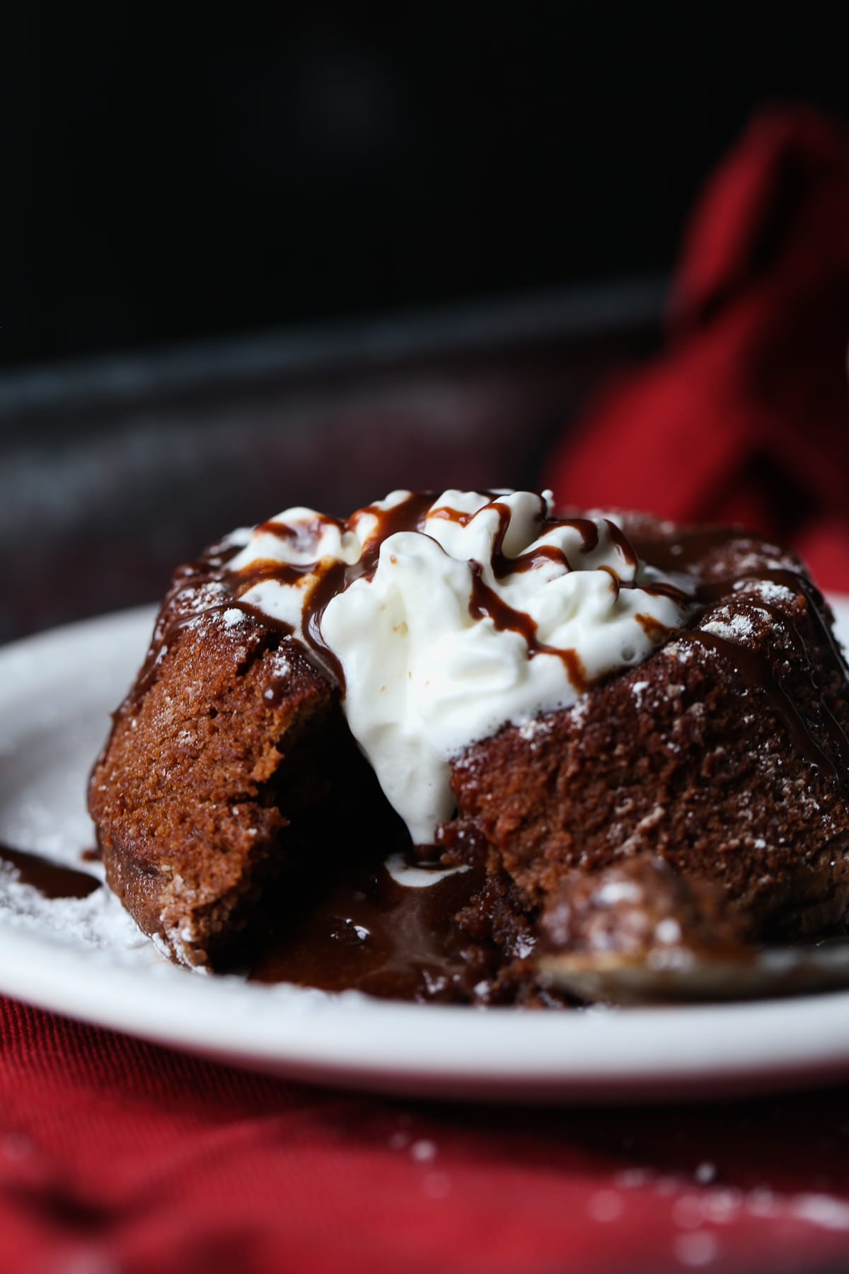 Vanilla ice cream on top of a chocolate lava cake, broken in half with melted chocolate filling.