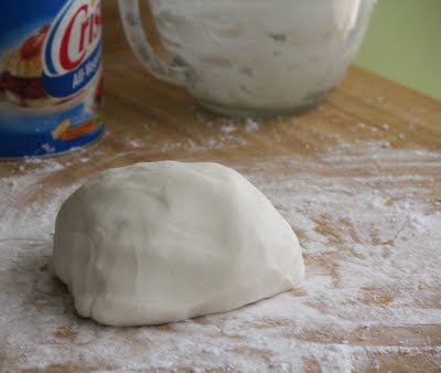 A round ball of marshmallow fondant on a lightly powdered wooden surface.