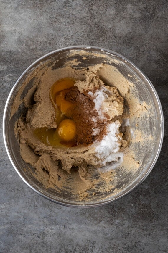 Eggs added to a metal mixing bowl with creamed butter and sugar.