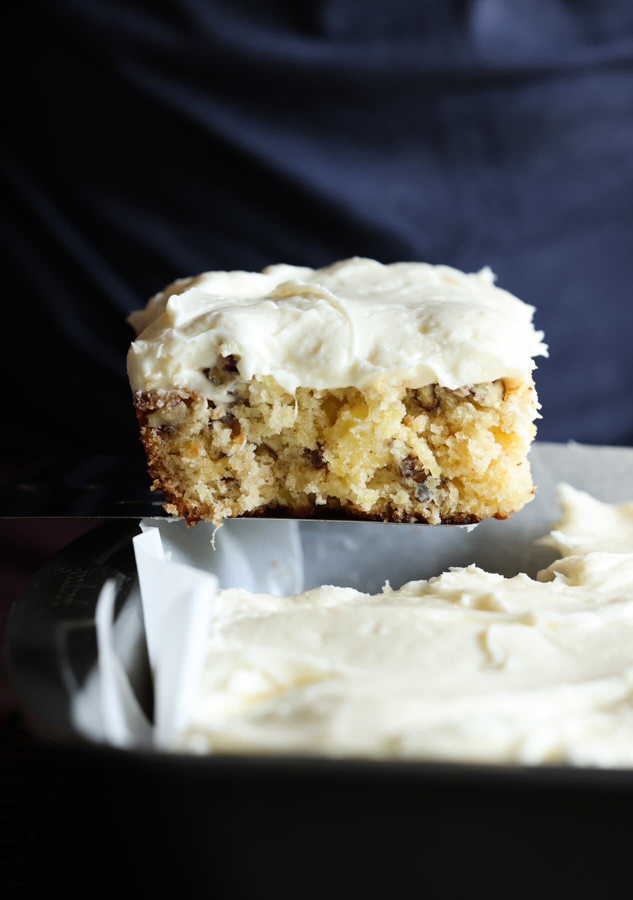 serving a piece of pineapple cake from a 9x13 baking pan with a spatula