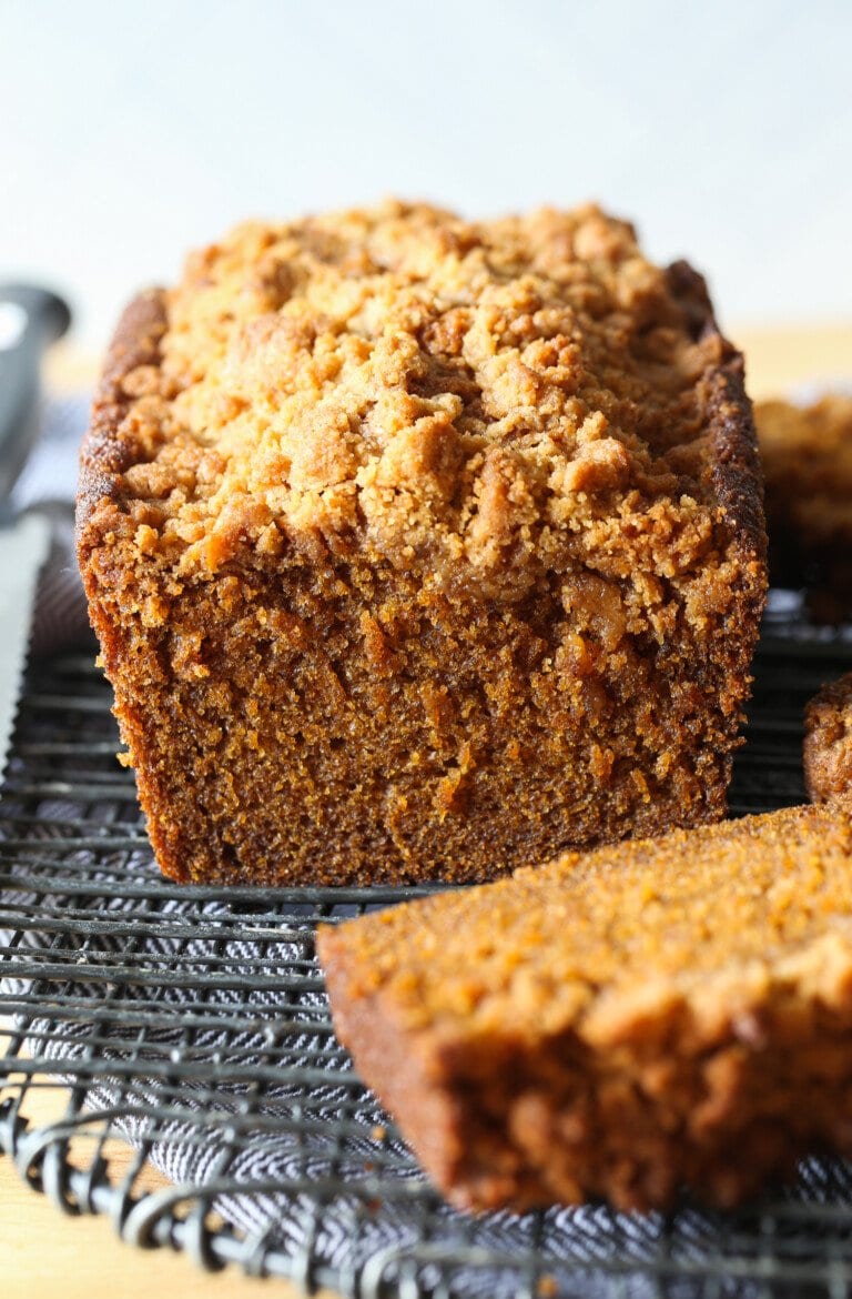 A slice cut from a loaf of pumpkin bread on a cooling rack.