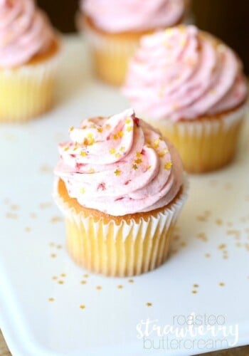 Assorted vanilla cupcakes topped with swirls of strawberry buttercream frosting.