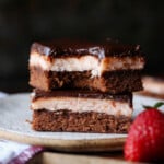 Layered Strawberry Brownies stacked on a plate with a bite taken out.