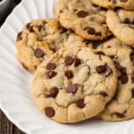 Subway cookies on a white plate next to a small bowl of chocolate chips.