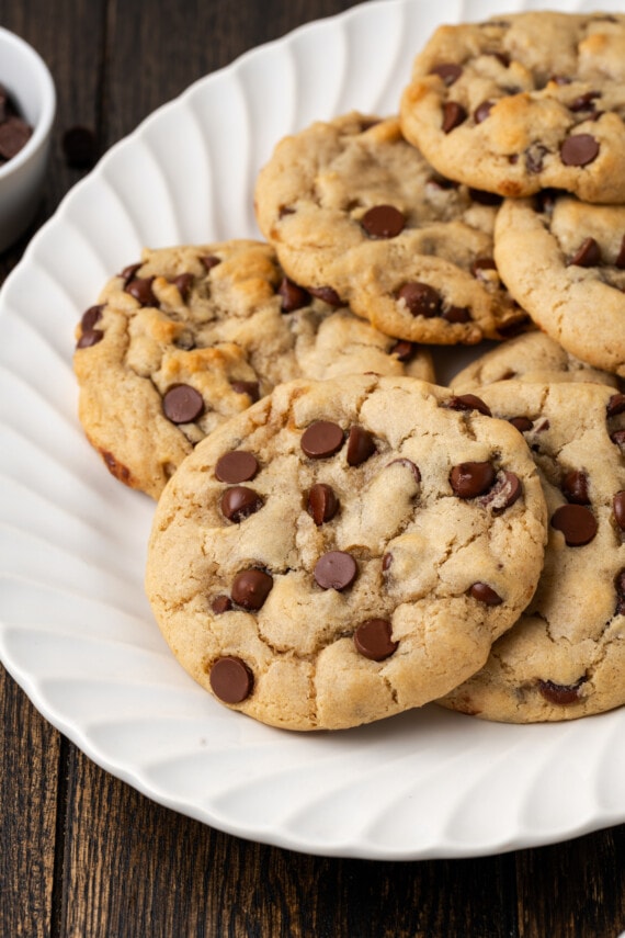 Subway cookies on a white plate next to a small bowl of chocolate chips.