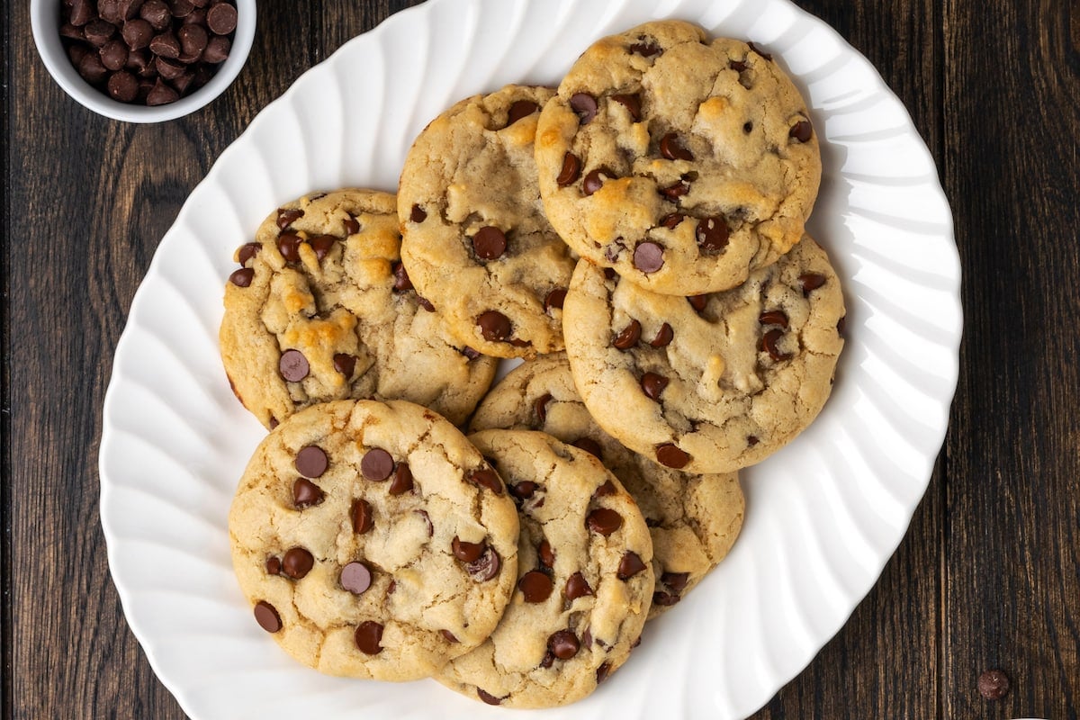 Overhead view of Subway cookies on a white plate next to a small bowl of chocolate chips.