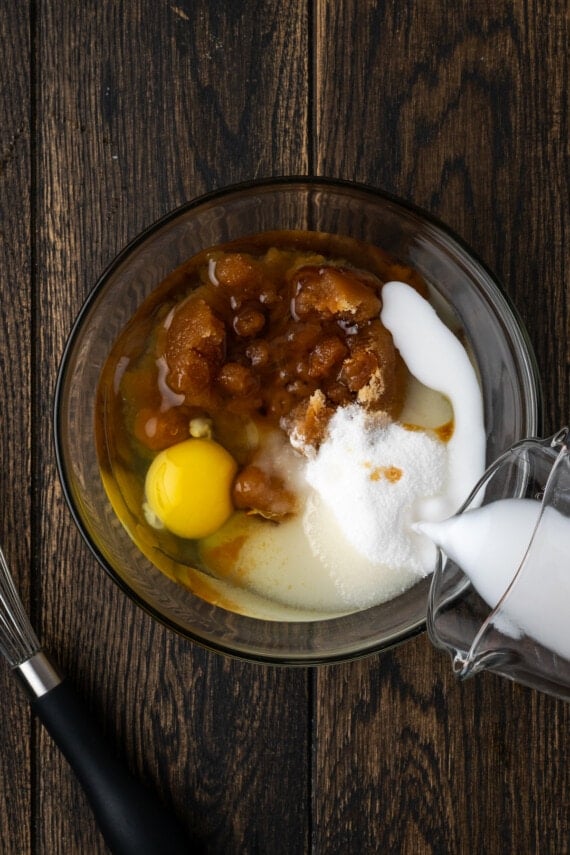 Milk is poured into wet ingredients in a glass bowl.