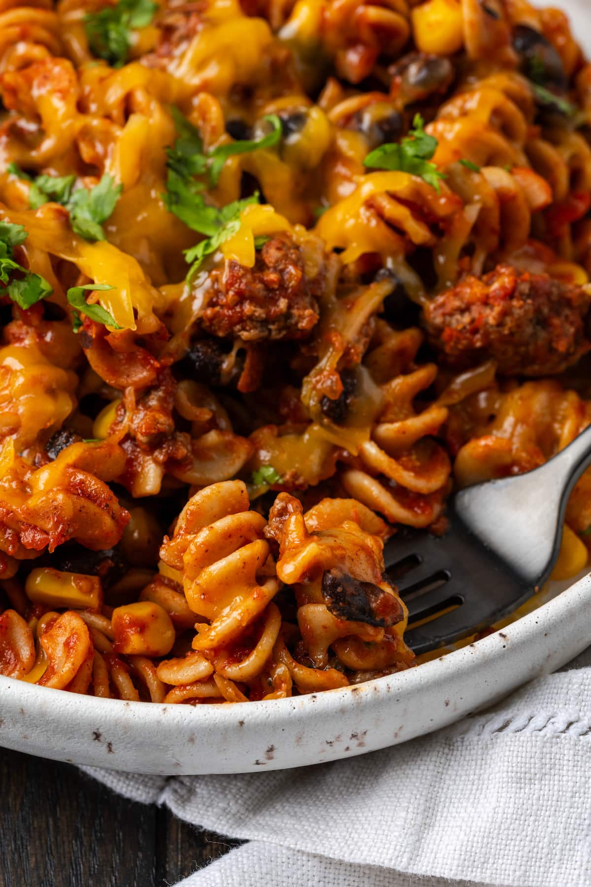 Close up of taco pasta in a white bowl with a fork.